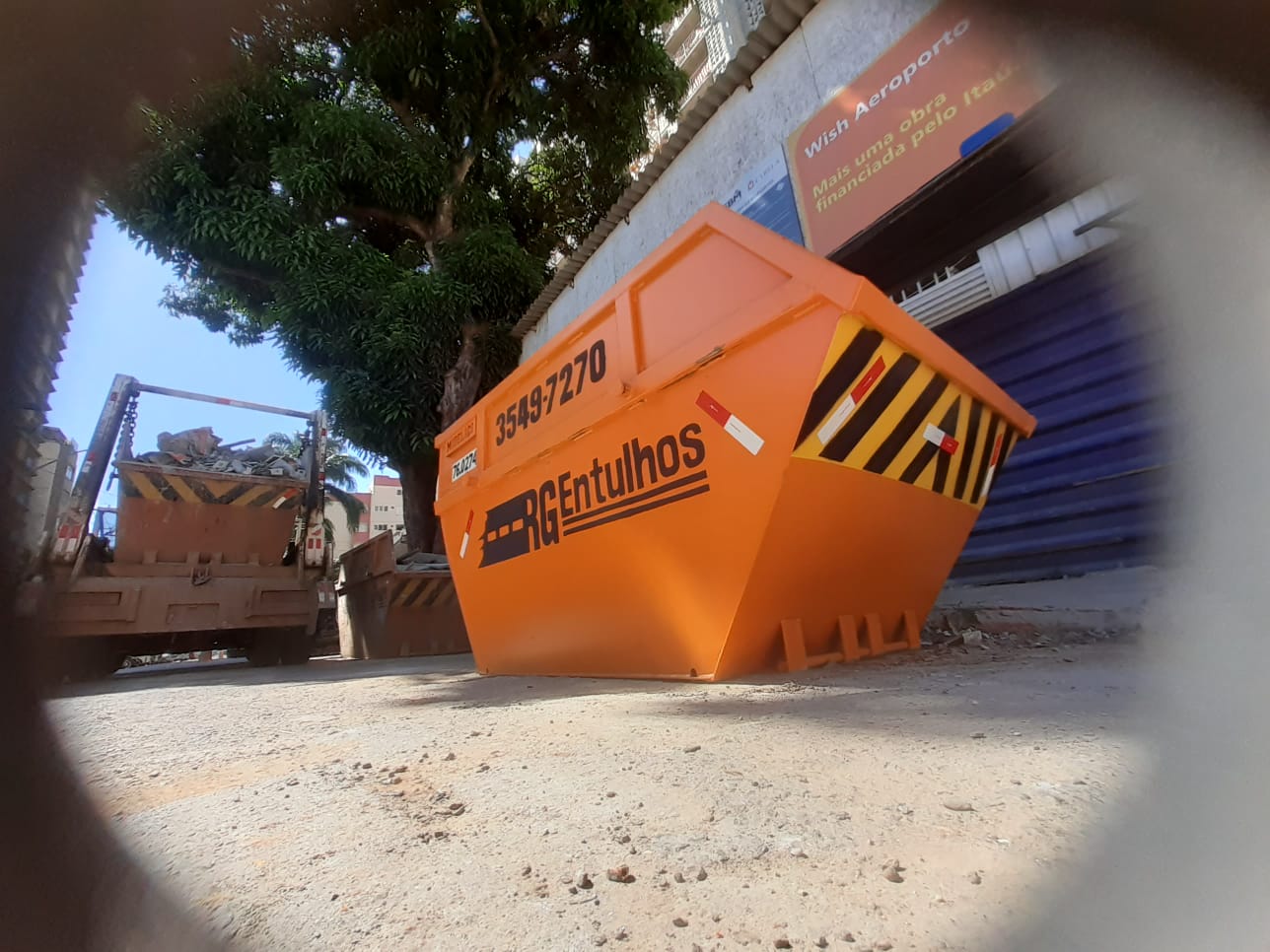 Caçamba laranja com resíduos de obra